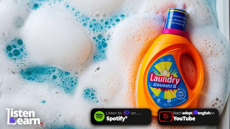 A bright orange laundry liquid bottle floating on soap suds. Fluent British English at Home.